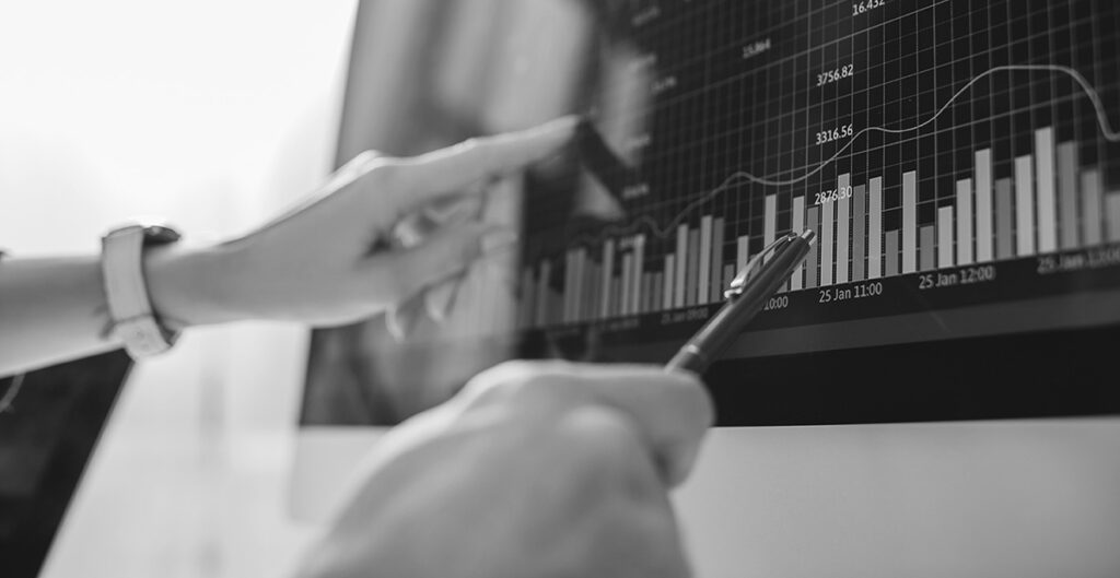 two hands pointing at a computer monitor with a graph